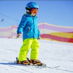 Young skier in helmet and goggles practicing on a beginner slope